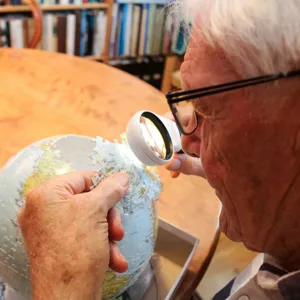 En eldre mann bruker lupe for å legge puslespill.