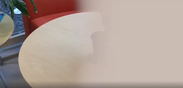 Et rundt bord med en rød stol. Høyre siden av bildet er uklart.