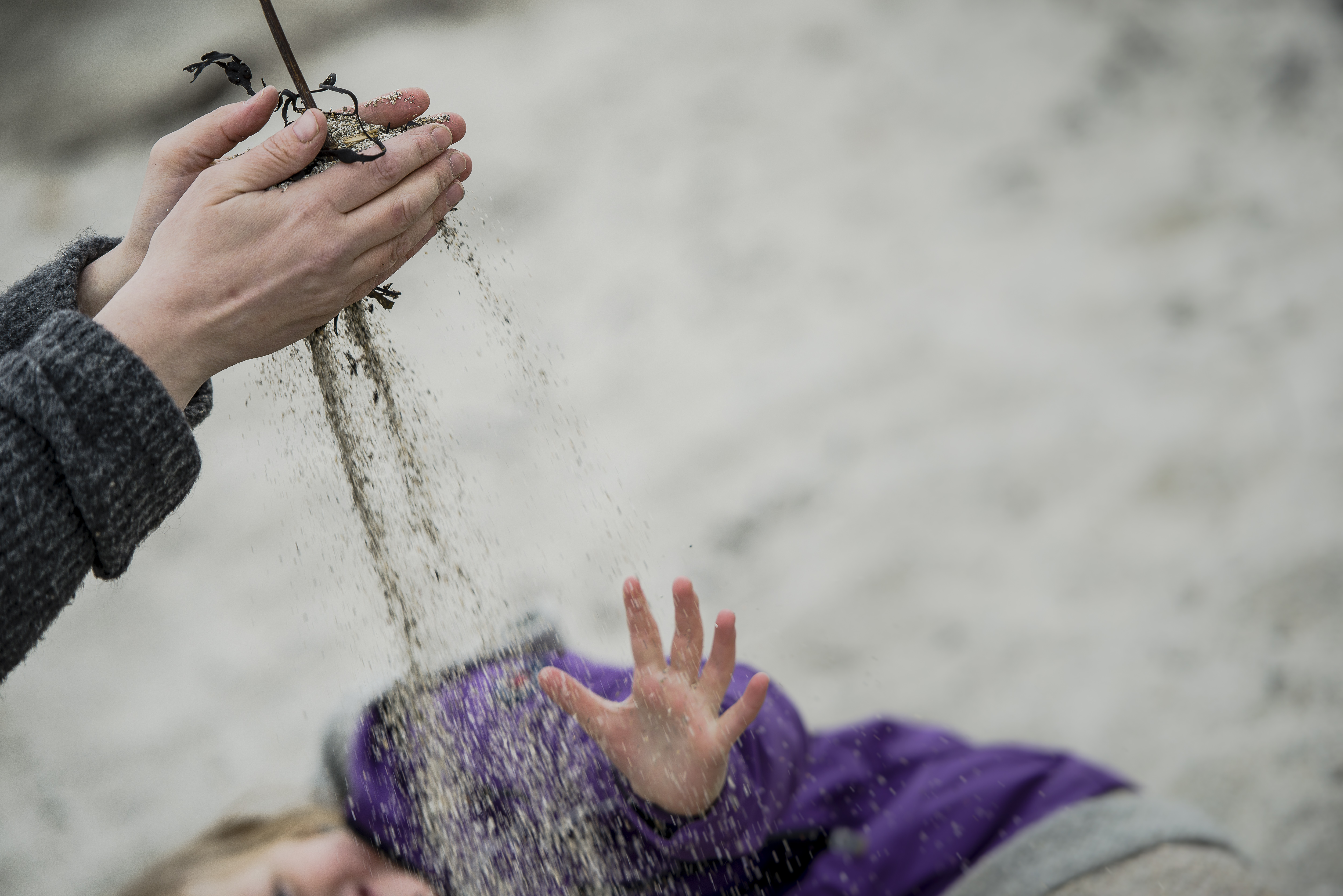 Hender som leker med sand.