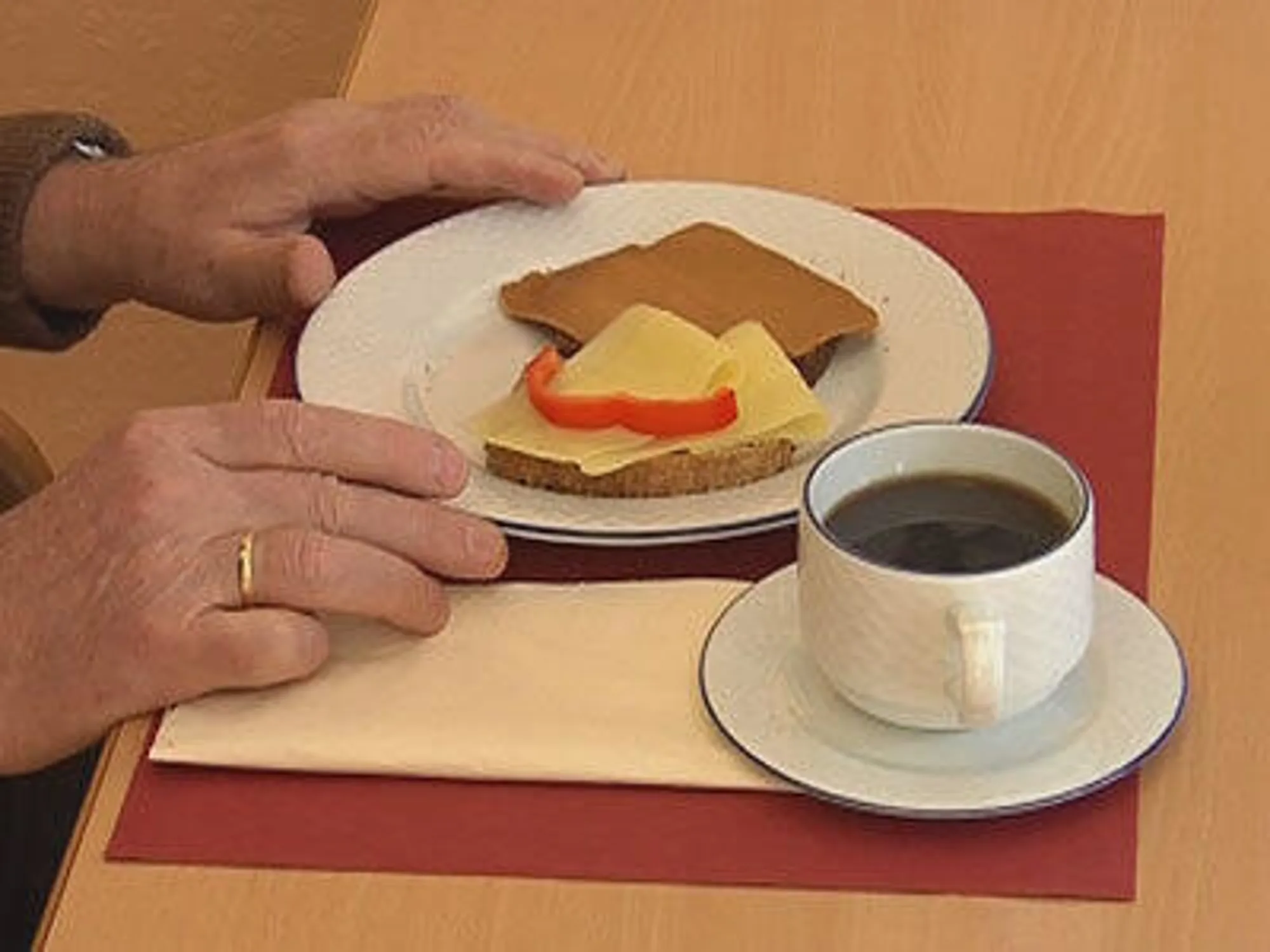 En person som holder en kopp kaffe ved siden av en tallerken med mat