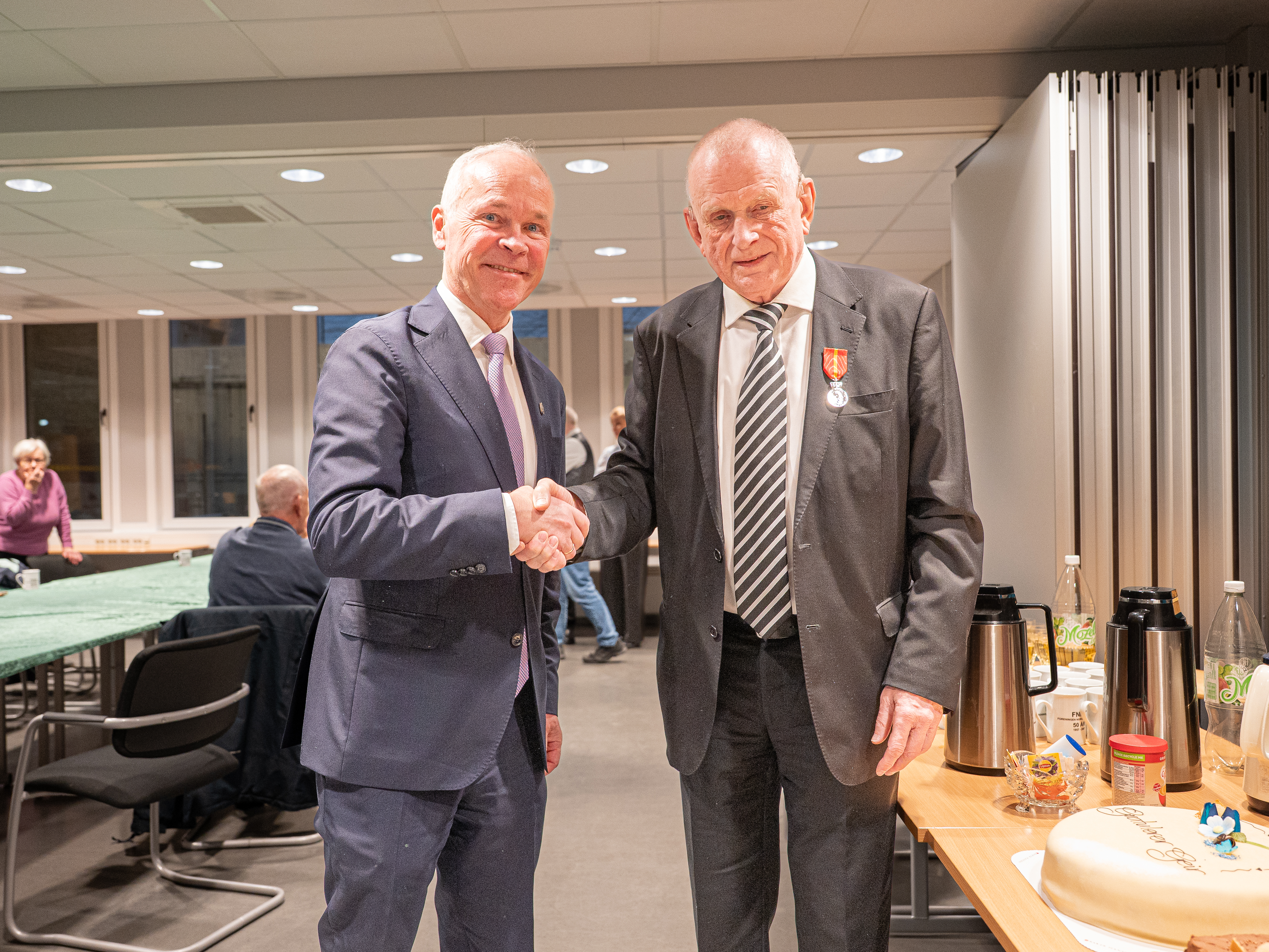 To menn i dress håndhilser på hverandre.