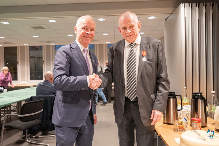 To menn i dress håndhilser på hverandre.