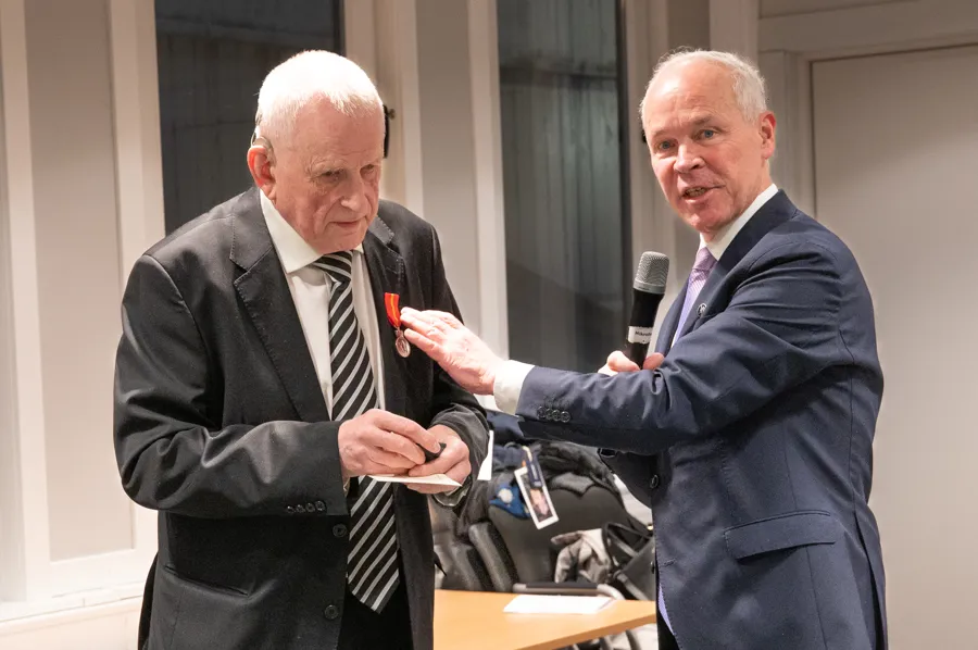 To menn i dress står ved siden av hverandre.
